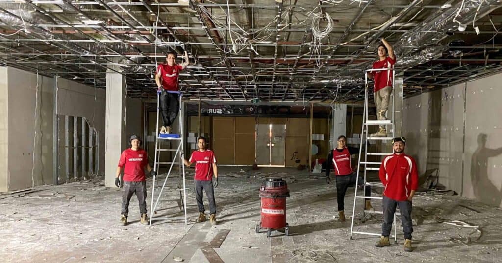 Six people peforming strip out demolition on the interior of a room