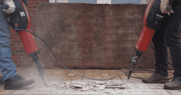 Two tradespeople removing tiles using jackhammers